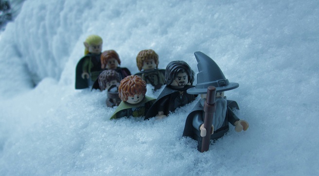 a photo of lego set up to look like the fellowship of the ring crossing a snowy mountain peak